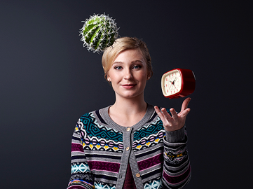 Kvinna jonglerar med en klocka och en rund kaktus.